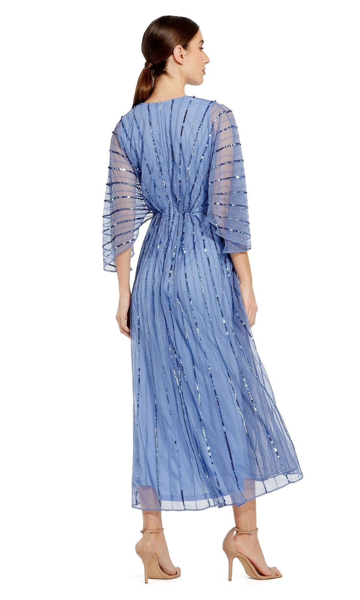 A woman in the Mac Duggal Periwinkle Blue Sequin Formal Dress 93995, featuring sequin stripes and kimono sleeves, poses side-back with nude heeled sandals.